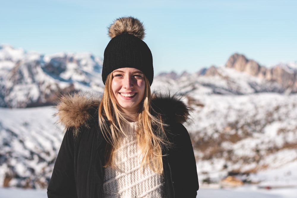 smiling woman standing while wearing black and brown parka coat