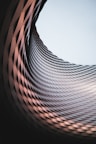 an abstract photo of a curved building with a blue sky in the background