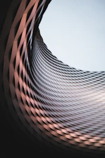an abstract photo of a curved building with a blue sky in the background