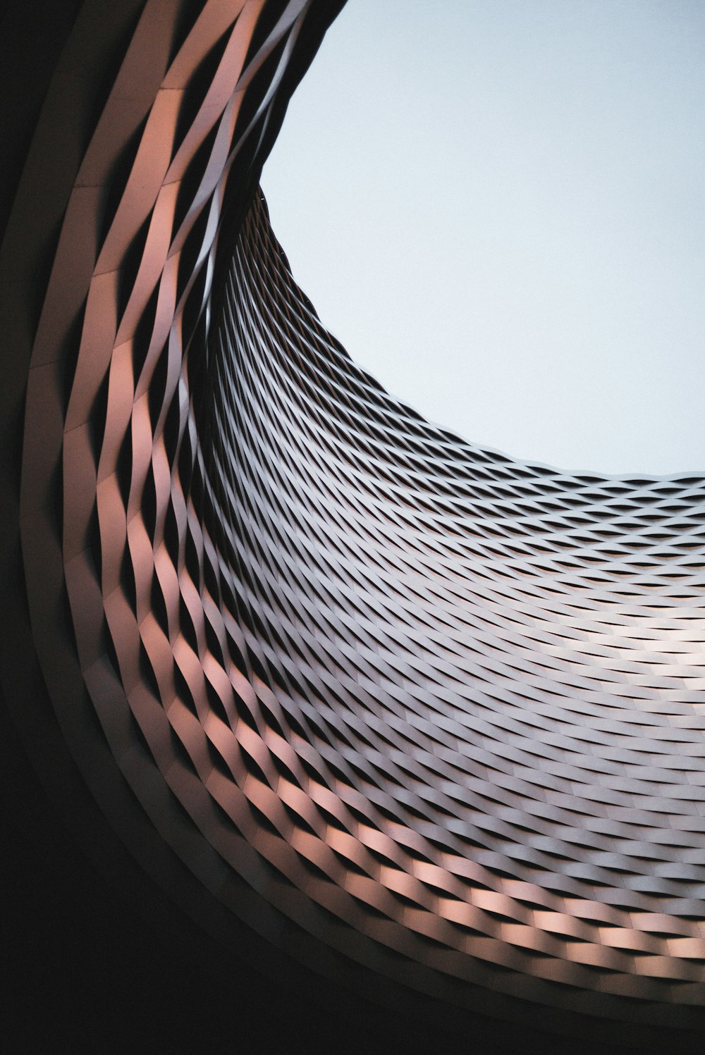 an abstract photo of a curved building with a blue sky in the background