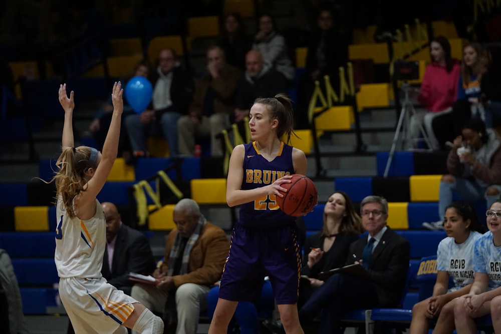 woman in blue and yellow basketball jersey holding basketball in court