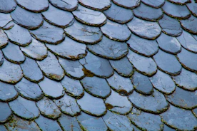 Technician inspecting and repairing a slate roof with specialized tools