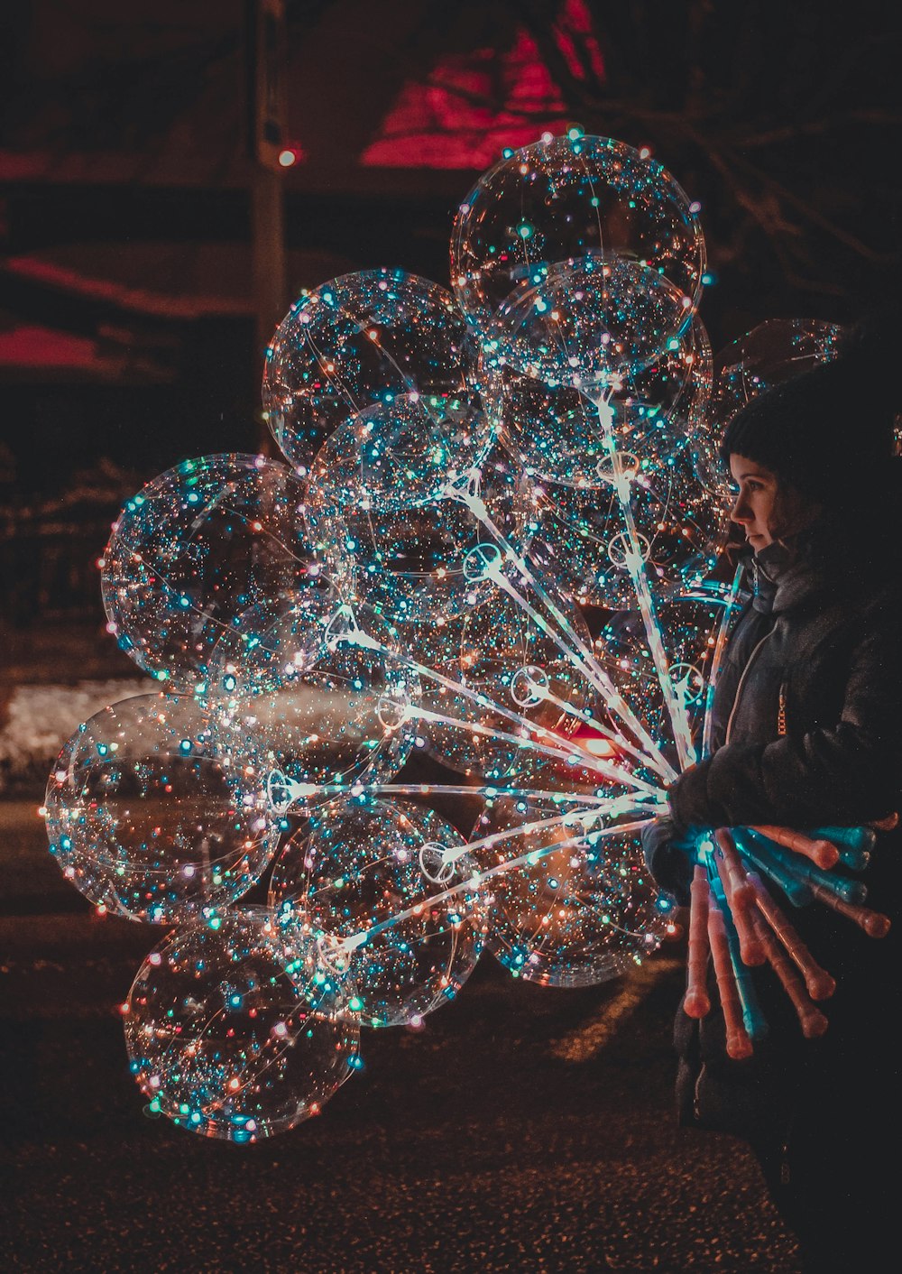 woman holding lighted balloons in dark surface