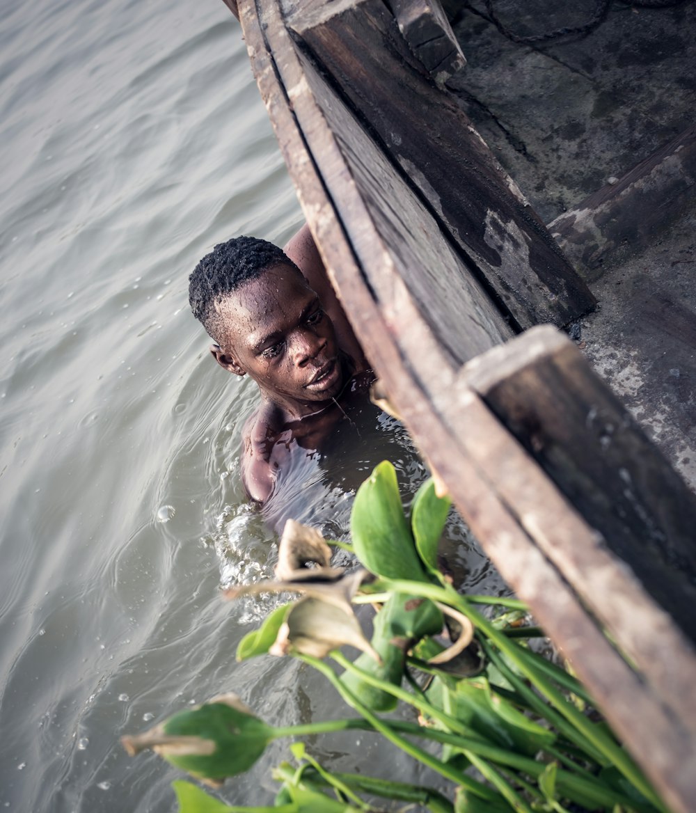 Homme dans le plan d’eau tenant sur le côté du bateau