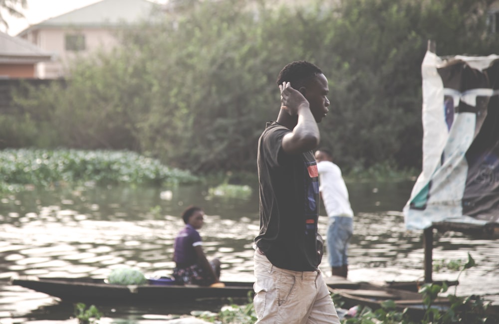 man in black t-shirt standing near two people riding on boat