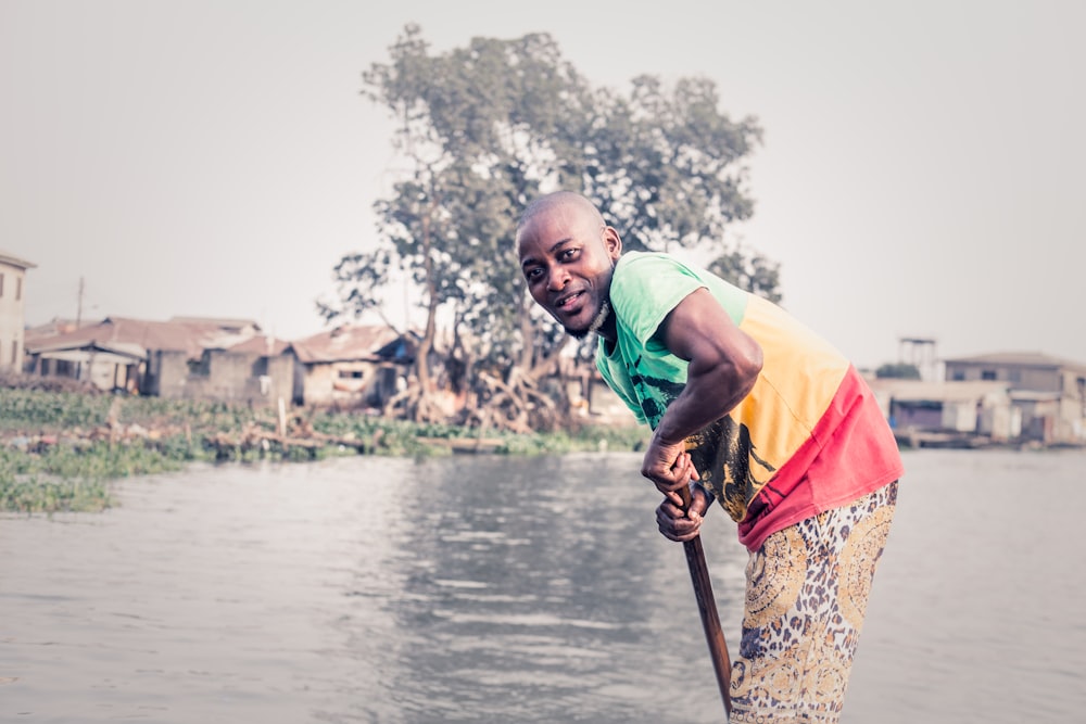 man in multicolored shirt holding boat stick