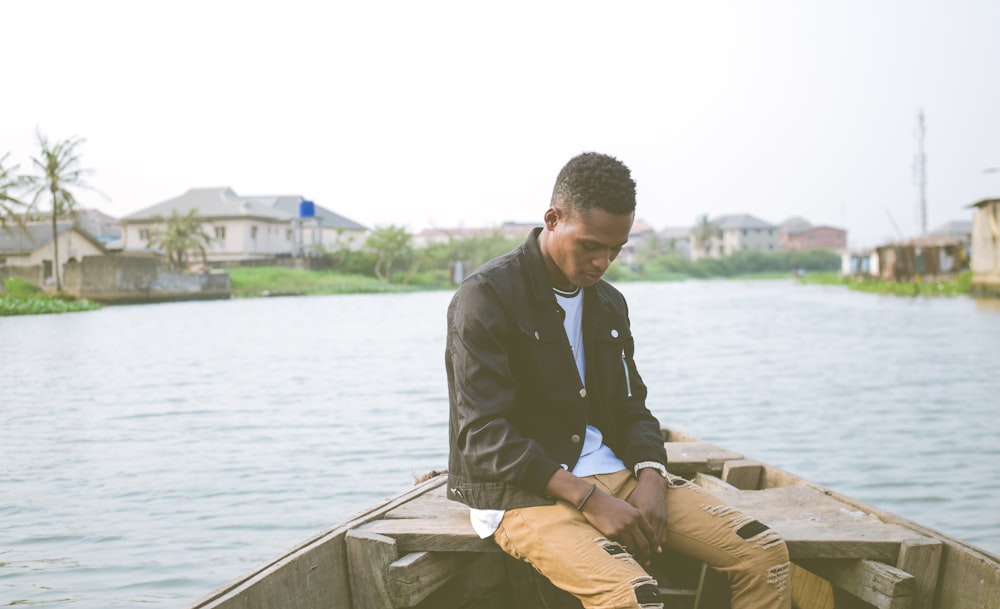 man wearing black jacket sitting on boat