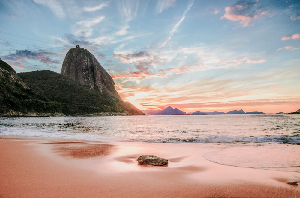 Montanhas perto do oceano sob nuvens brancas durante o dia