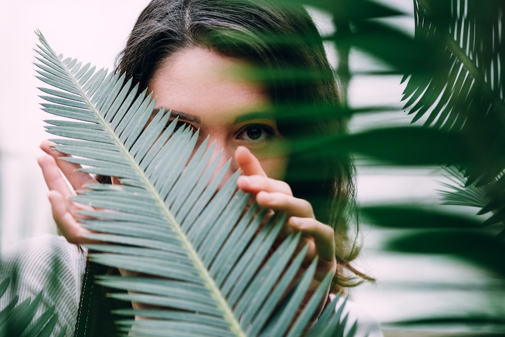woman hiding behind green palm leaves