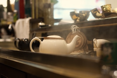 Electric kettle steaming gently beside fresh spices and herbs in a bright kitchen.