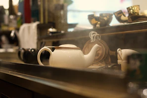 A cozy kitchen scene featuring a bright stoneware teapot surrounded by fresh flowers and a linen cloth.