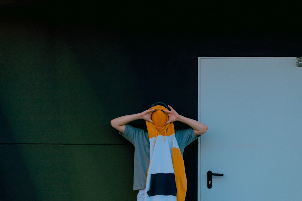 person holding white, orange, and black pullover hoodie