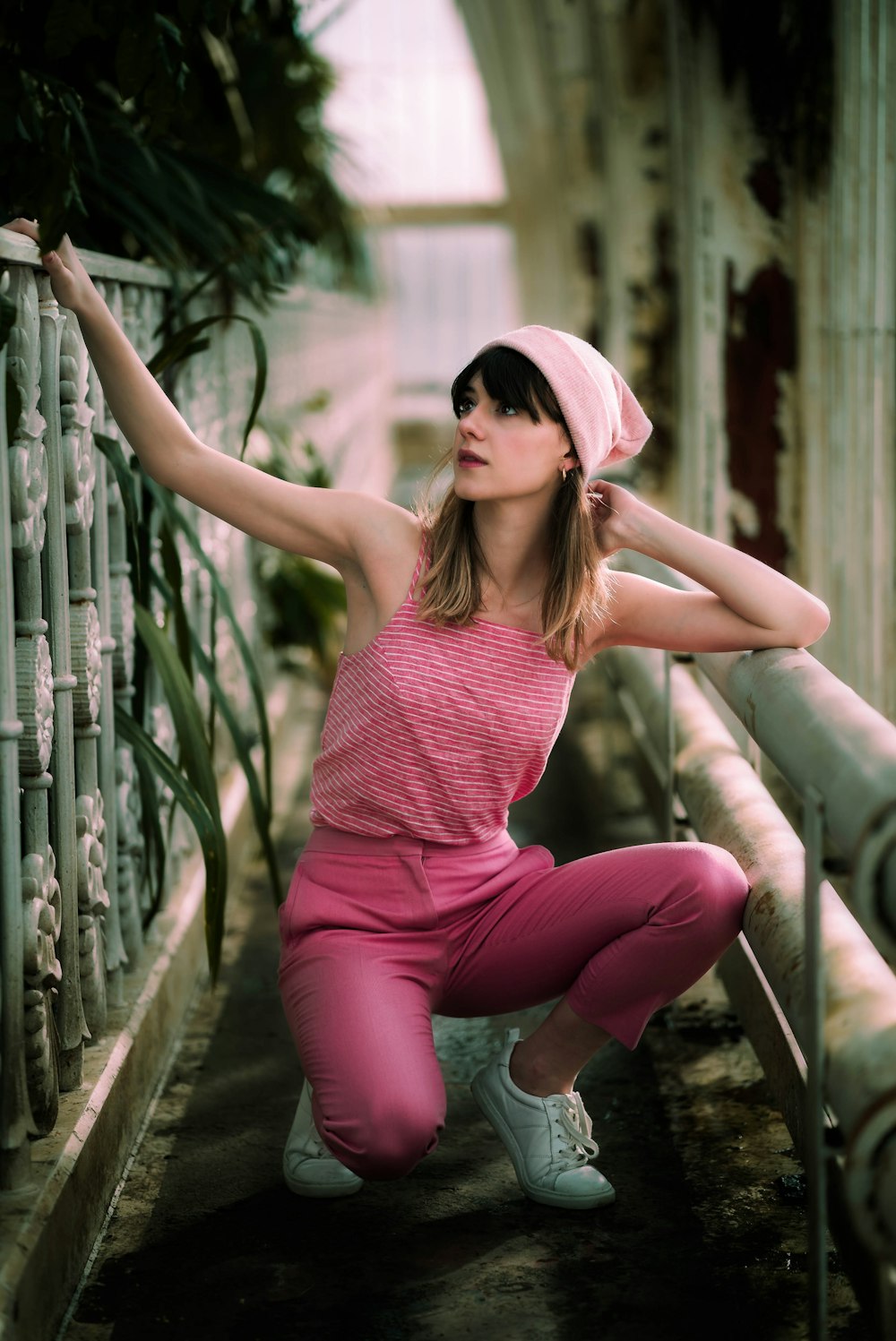 woman in pink pants sitting beside railings