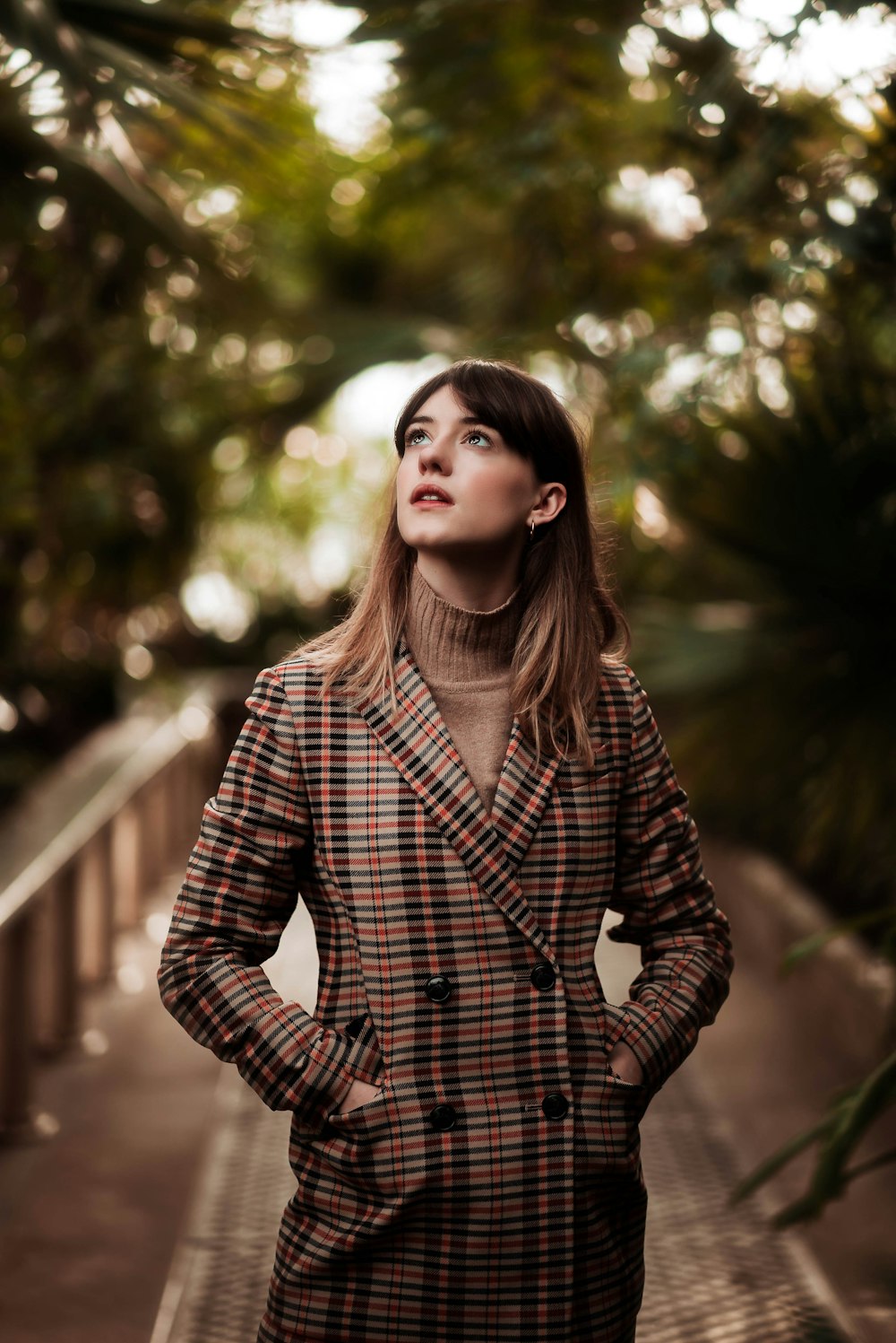 selective focus photography of woman wearing brown button-up coat looking upwards