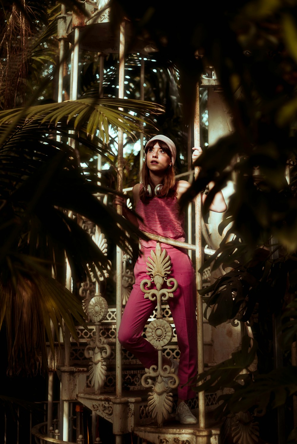 woman standing on stair case holding metal bars near plants