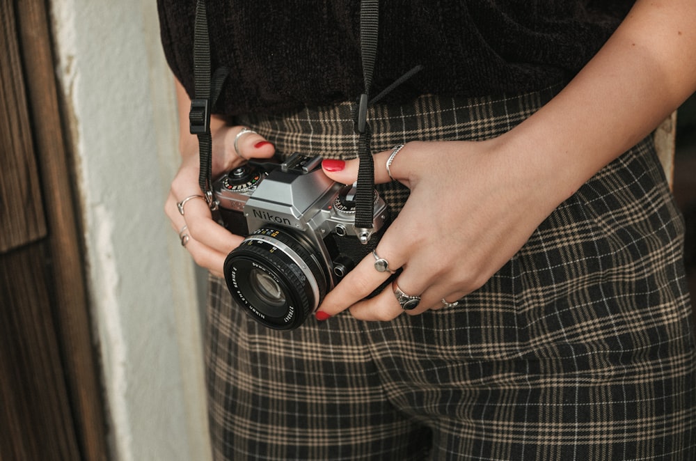 person holding Nikon camera with black strap