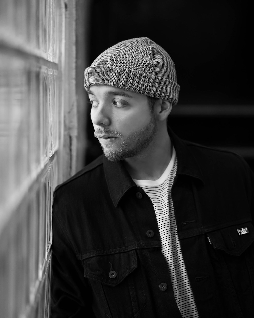 grayscale photography of man leaning on window