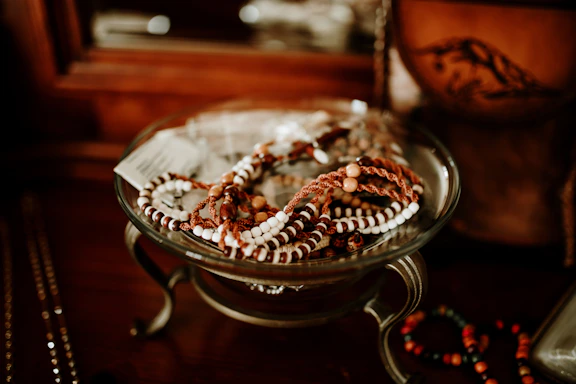 A stack of colorful beaded bracelets arranged artfully on a vintage ceramic dish.