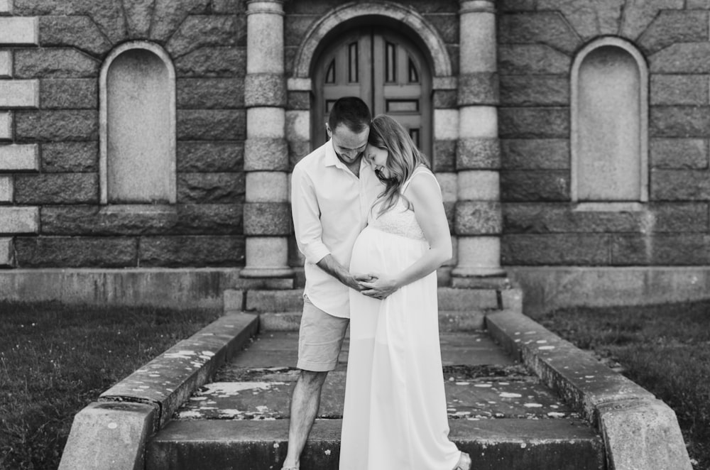 grayscale photography of man touching woman's pregnant belly