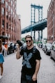 smiling man holding DSLR camera carrying backpack near parked cars during daytimes