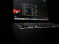Close-up of a hand uploading music files on a laptop with streaming platforms on the screen.