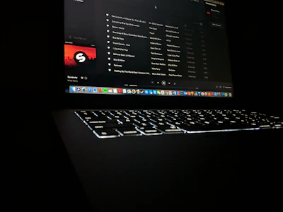 Close-up of a hand uploading music files on a laptop with streaming platforms on the screen.