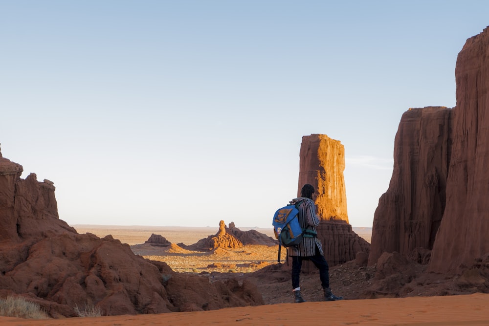 man standing near rock monolith