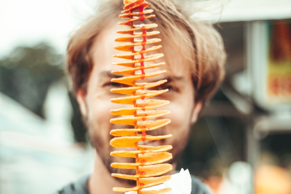 Homme souriant derrière des frites empilées pendant la journée