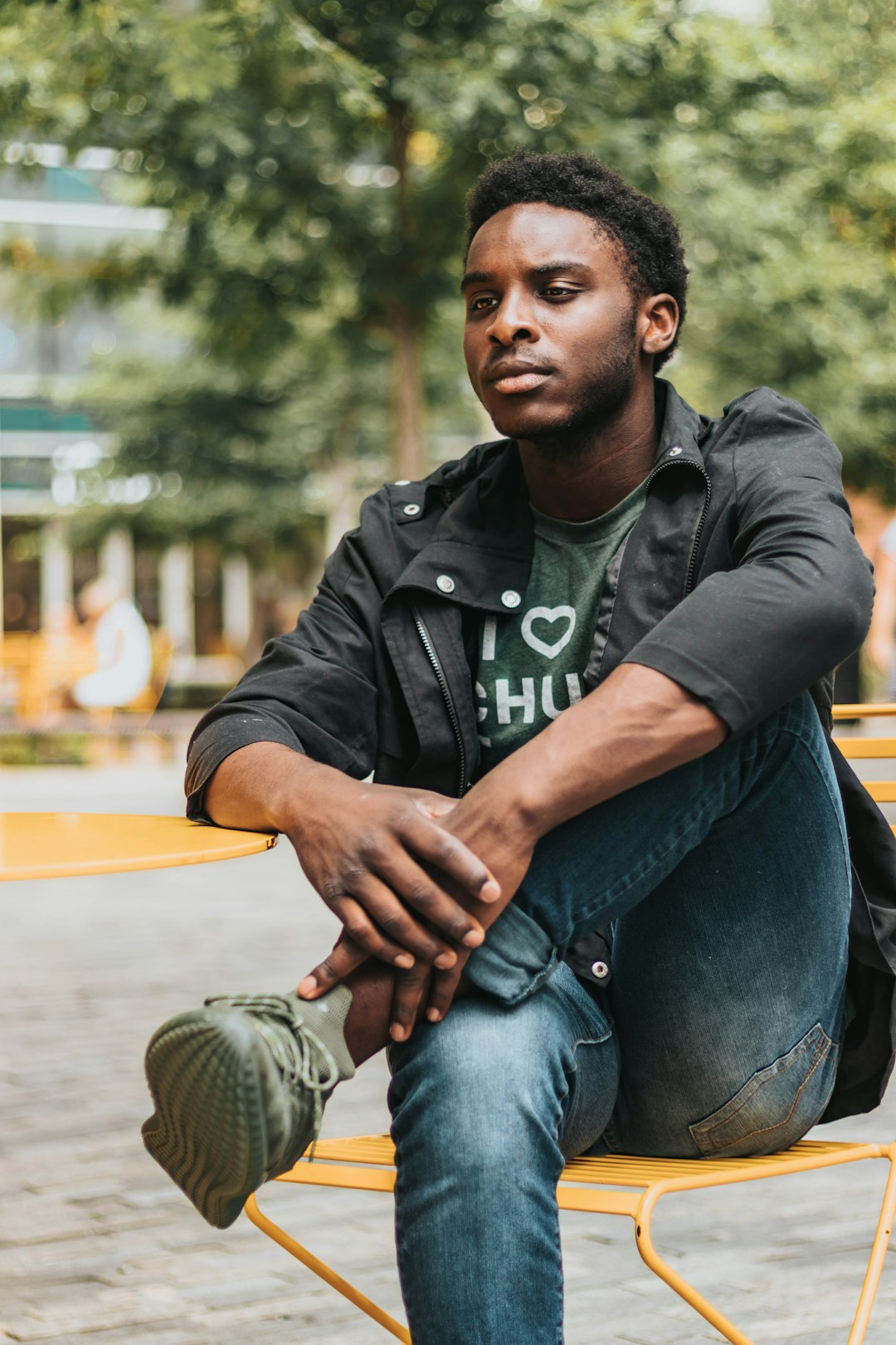 man in black jacket sitting on yellow metal chair