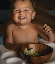 toddler eating vegetable in bowl