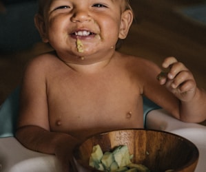 toddler eating vegetable in bowl