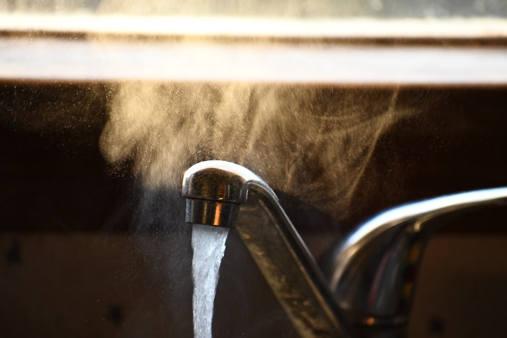 selective focus photography of turned-on faucet