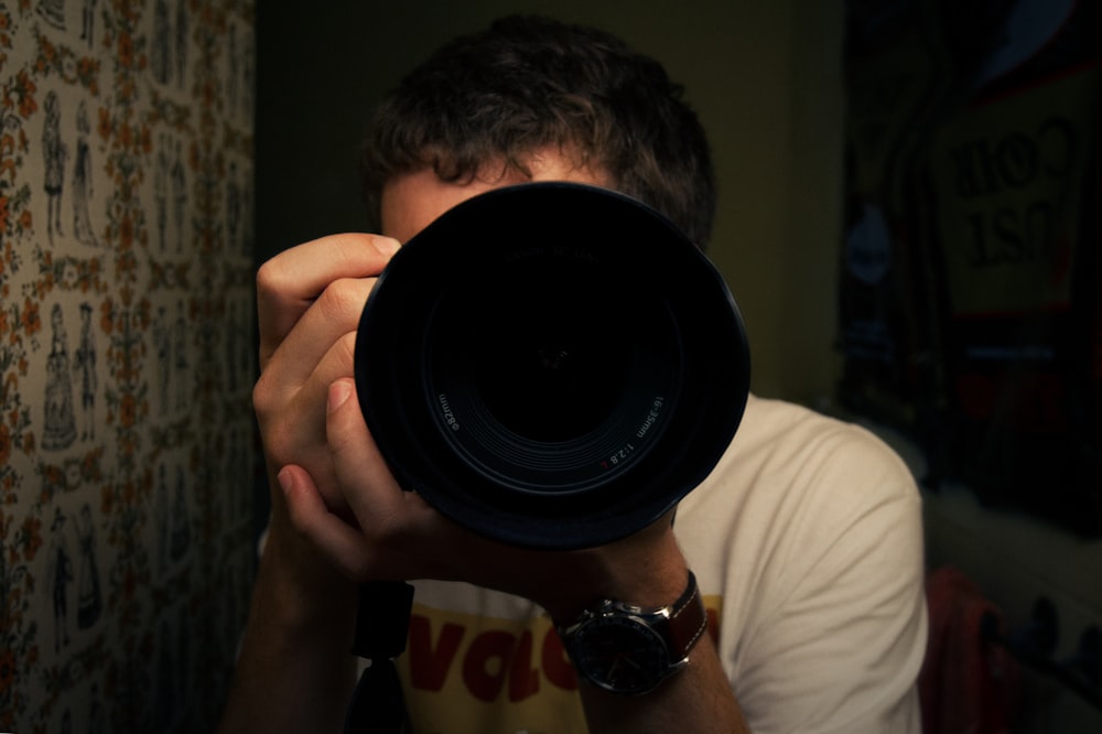 man behind camera talking photo of himself in front of mirror inside dark room