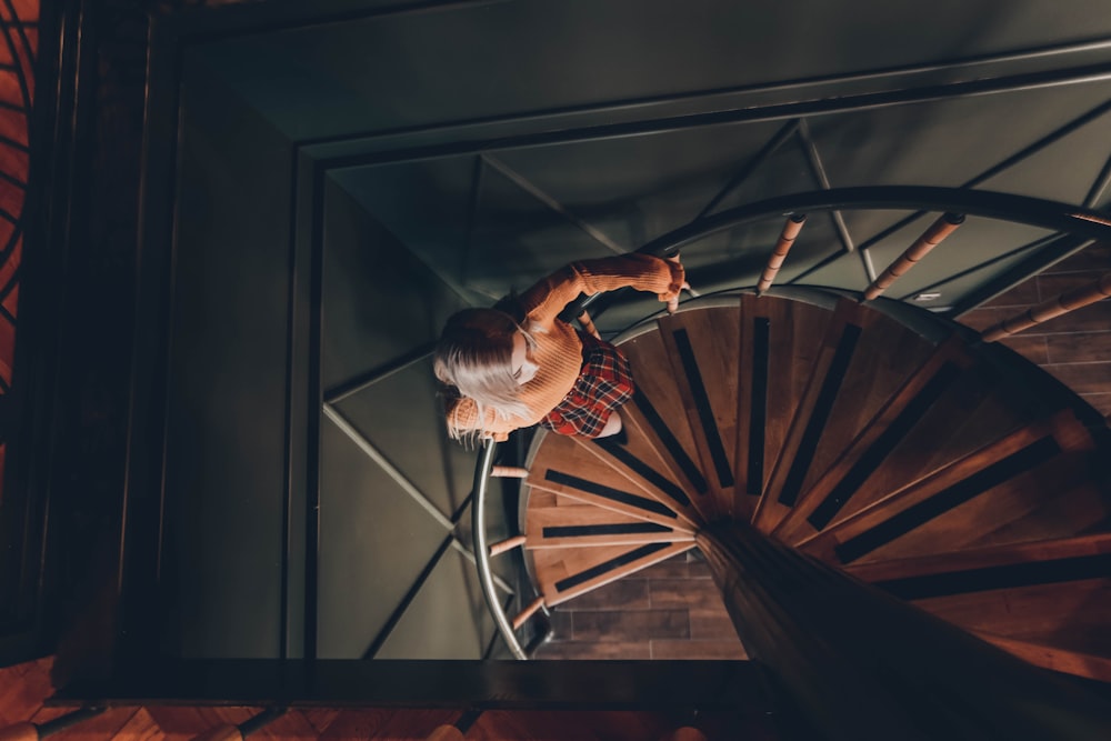 high angle photography of woman standing on spiral stairs