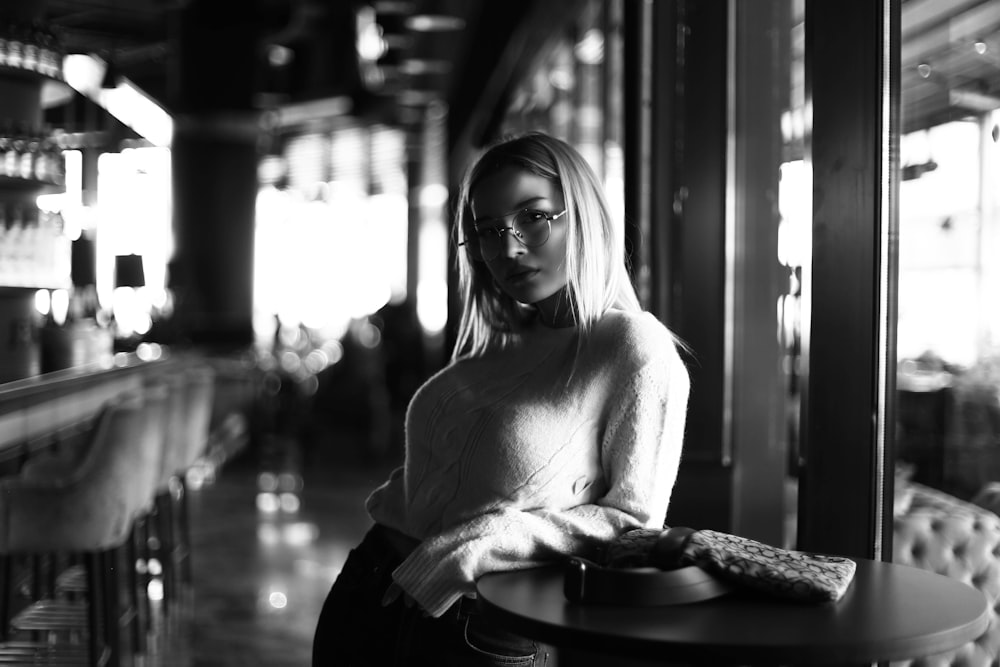 grayscale photography of woman leaning on table