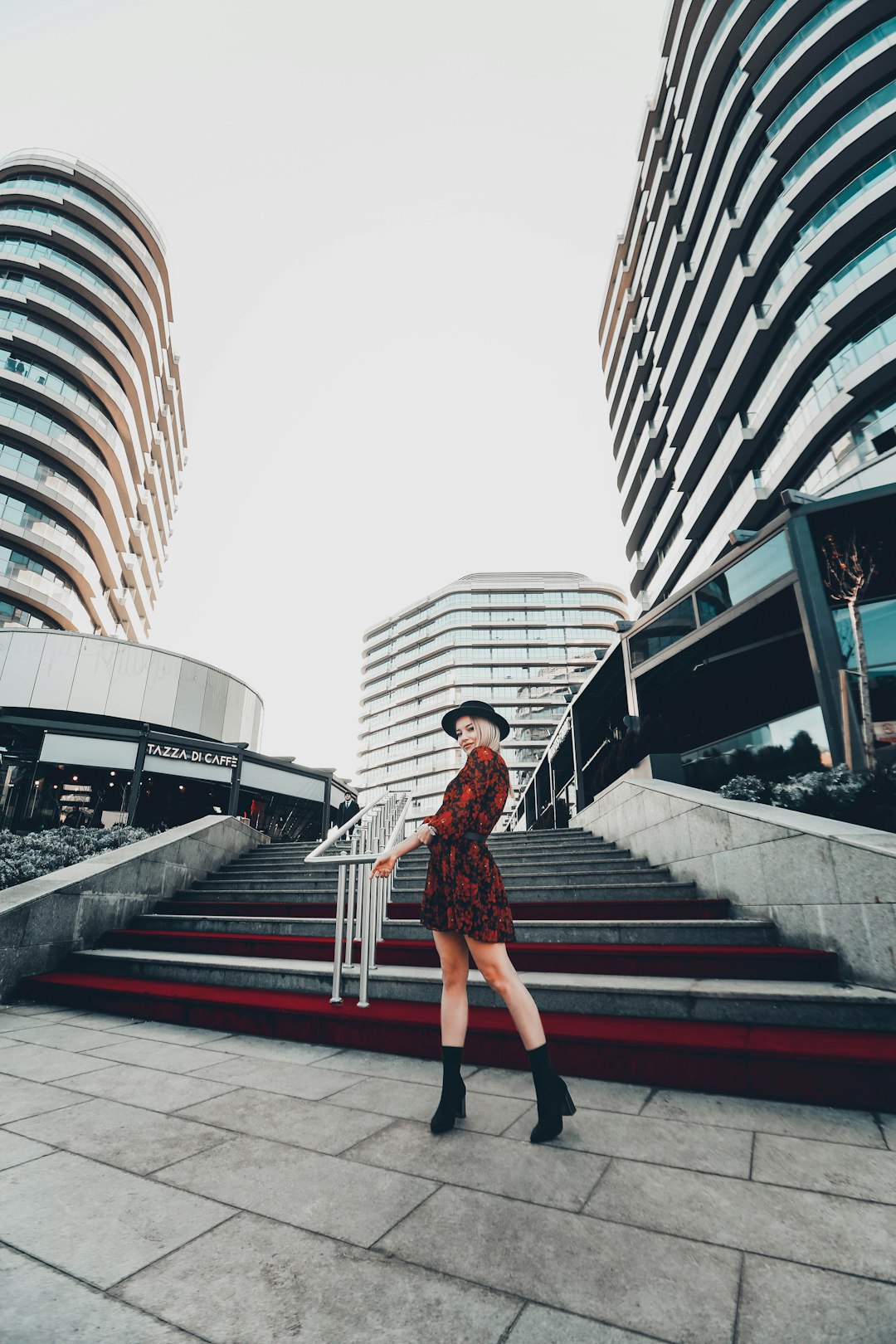 woman in floral dress standing in front of concrete stairs overlooking buildings