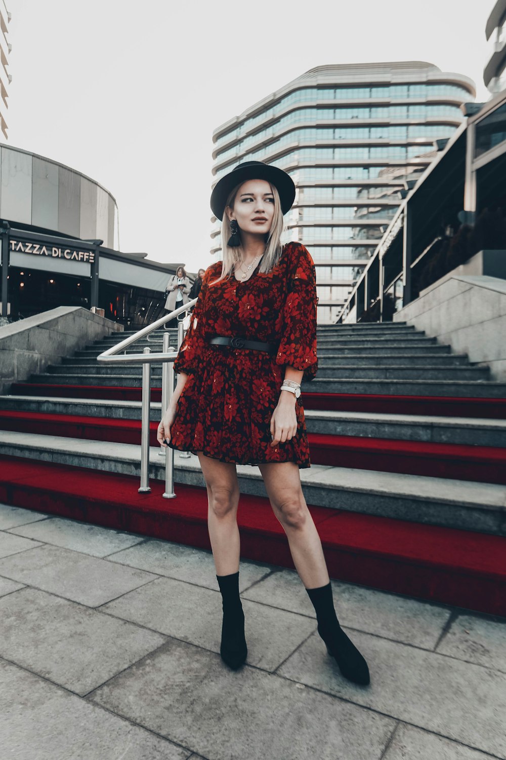 woman in red and black floral dress standing near stairs