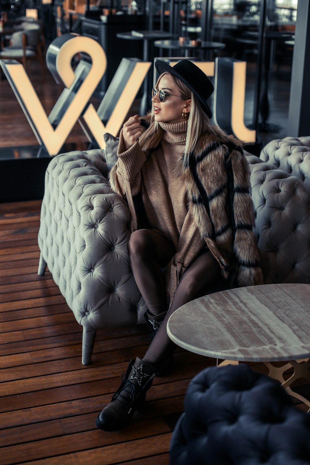 woman sitting on tufted sofa chair wearing fur coat