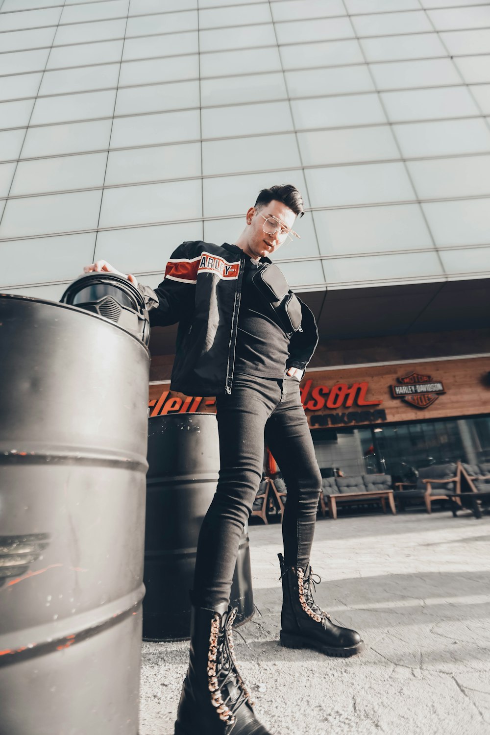 man wearing black leather boots standing near barrel