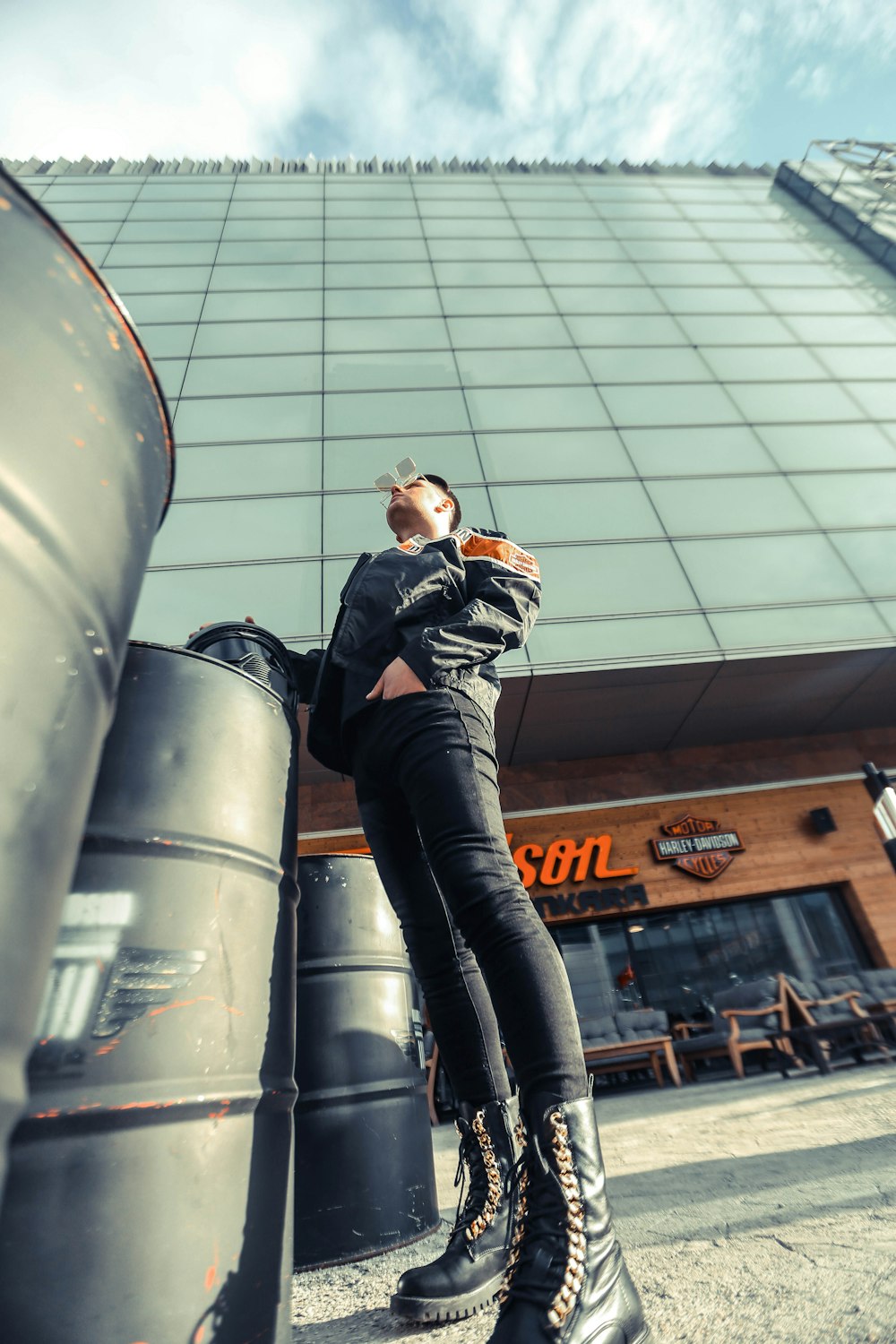 low-angle photography of man standing beside barrel near building