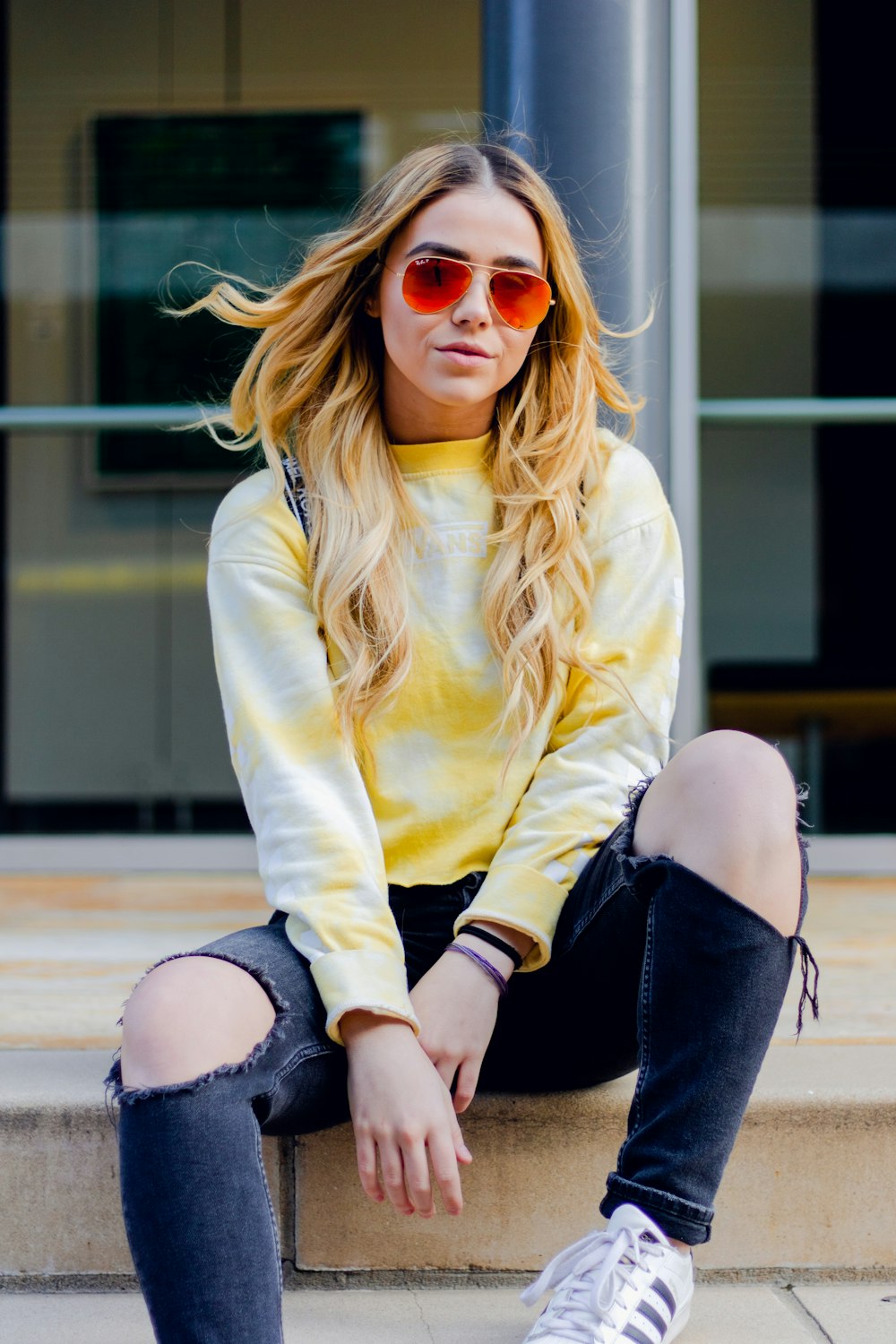 woman sitting on beige surface wearing white and yellow long-sleeved shirti