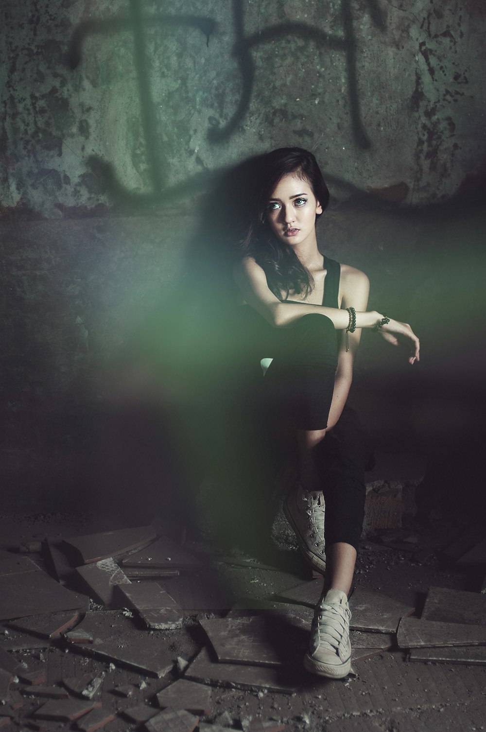 woman in black tank top sitting and leaning by the wall