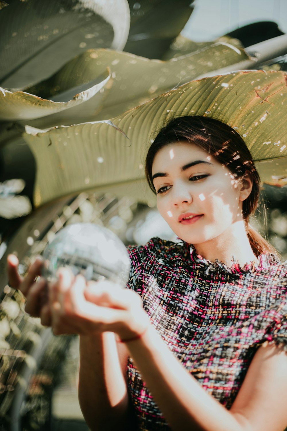 woman holding water globe under banana leaf