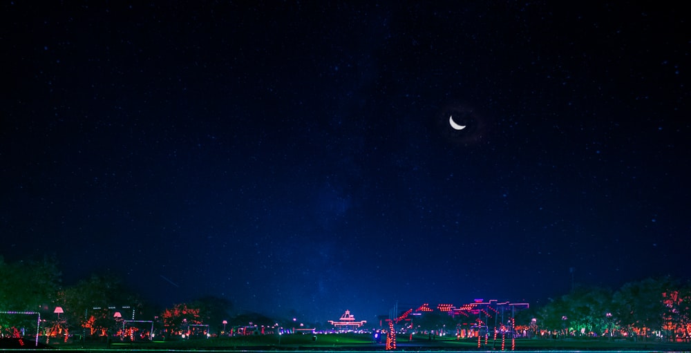 a view of a city at night with the moon in the sky