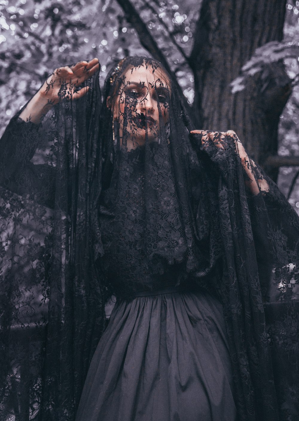 woman wearing lace veil under tree