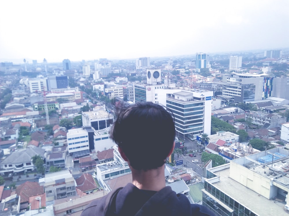 man standing at rooftop overlooking city