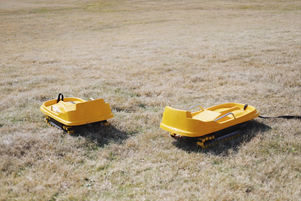 two yellow vehicle toys on green grass field