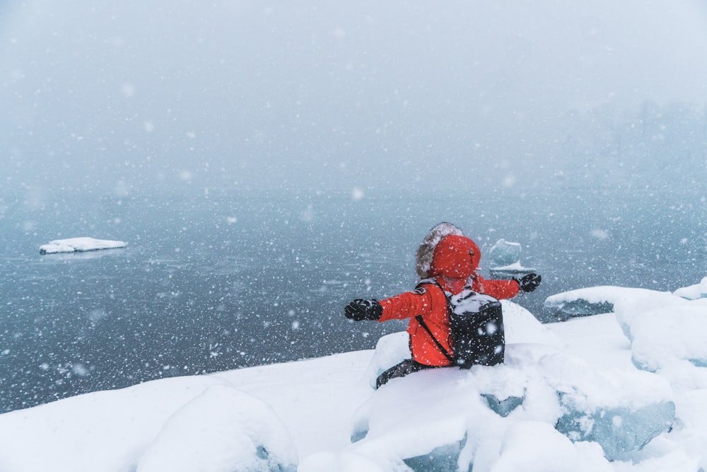 person in red hoodie sitting on snowfield