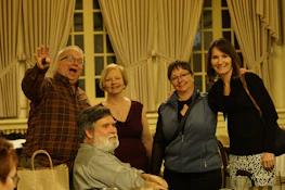 Smiling faces of people from different ages gathered in a bright room.