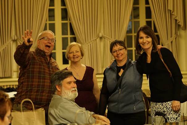 A group photo of the cast and crew smiling warmly after a community theatre show.
